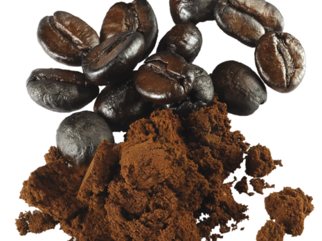 Hier sieht man einige geröstete Kaffeebohnen neben Kaffeekohle