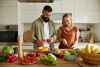 Eine junge Frau und ein junger Mann stehen in der Küche und schneiden Gemüse für eine Low-Fodmap-Ernährung
