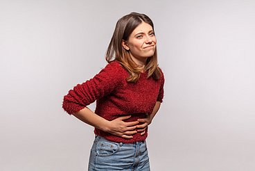 Frau mit Blähungen Frau hält sich den Bauch aufgrund schmerzhafter Blähungen © khosrork / adobe.stock