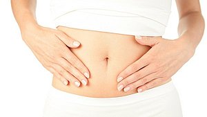 Eine Frau führt eine Bauchmassage durch zur Entspannung